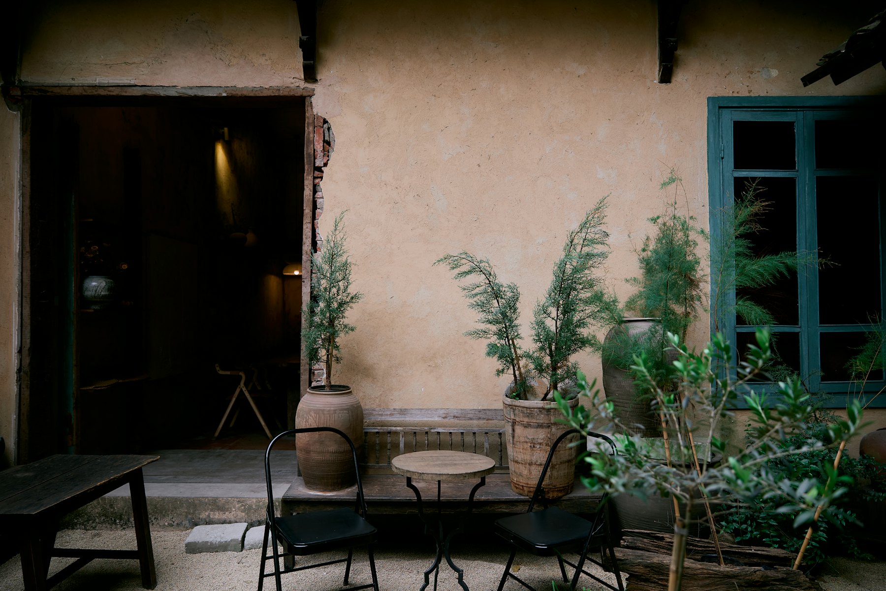 A quiet courtyard with a small round table, two chairs and potted plants